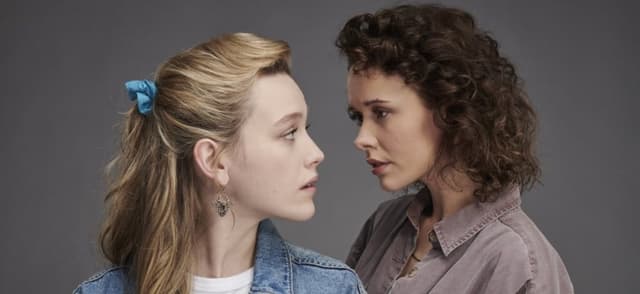 Dani and Jamie stand close and gaze into each other's eyes