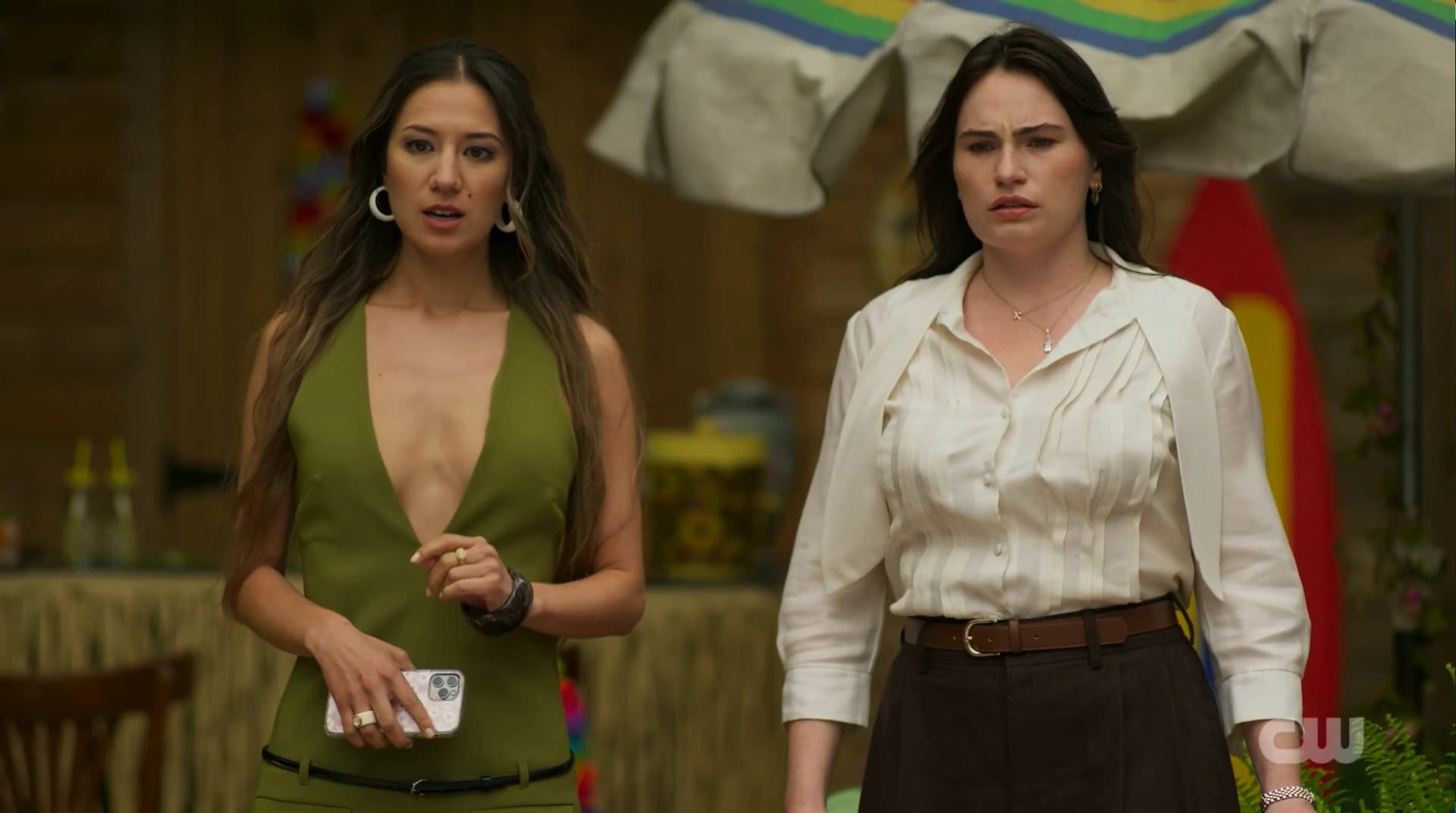 Two women are standing side to side, slightly surprised.